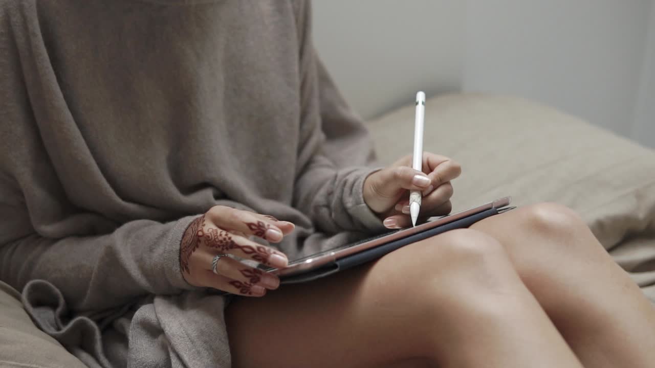 Woman Drawing on Tablet in Bed