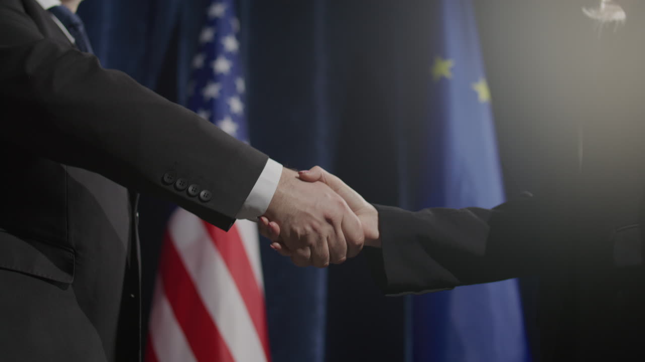 Formal Handshake between Political Leaders in front of US and EU Flags