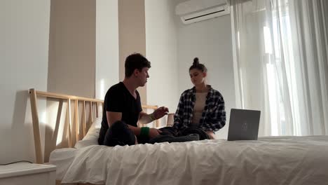 una pareja sentada en la cama hablando.