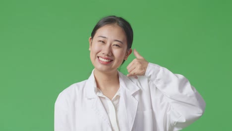 woman in lab coat making phone gesture