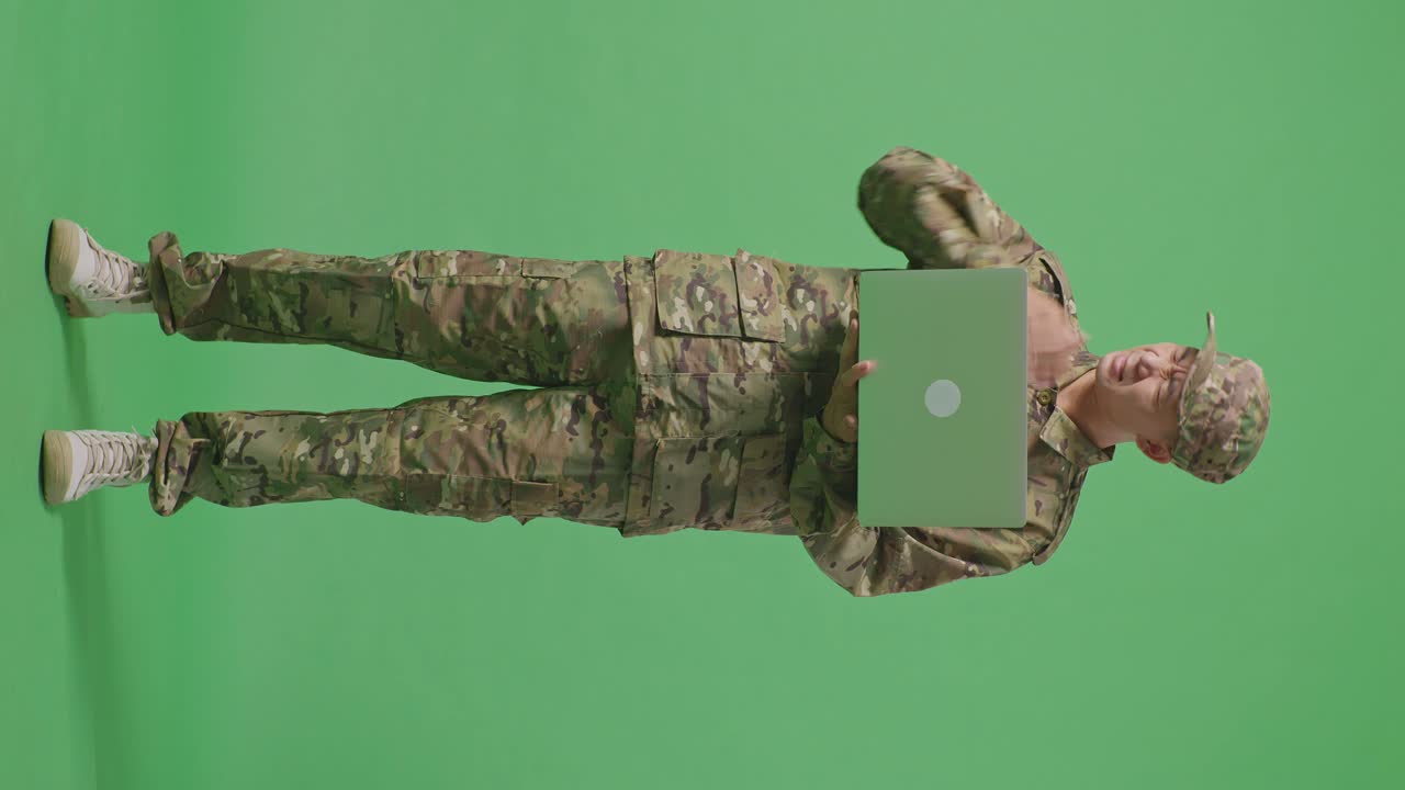 Full Body Of Asian Man Soldier Using A Laptop And Having A Headache While Standing In The Green Screen Background Studio