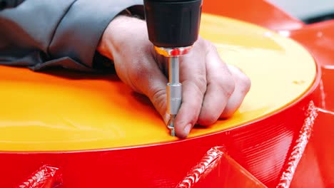 Worker-with-screwdriver-and-bit-screwing-screw-into-product-at-factory