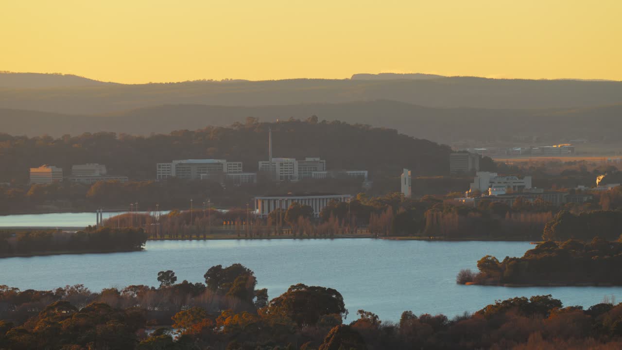 Canberra landmarks light up as golden morning light reflects off Lake Burley Griffin in this wide tranquil view of the capital