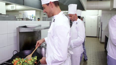 un chef sonriente freyendo verduras en un wok