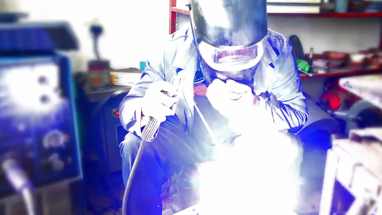 Technician worker working wearing industrial uniforms and Welded Iron Mask at Steel welding plants with sparks flying, industrial safety first concept.