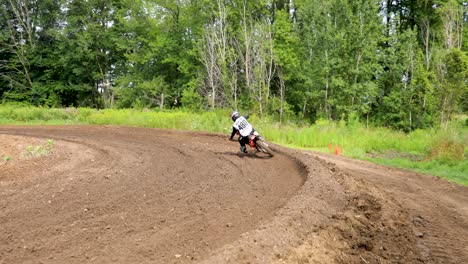 piloto de motocross entrando y saliendo de un giro de tierra en una pista