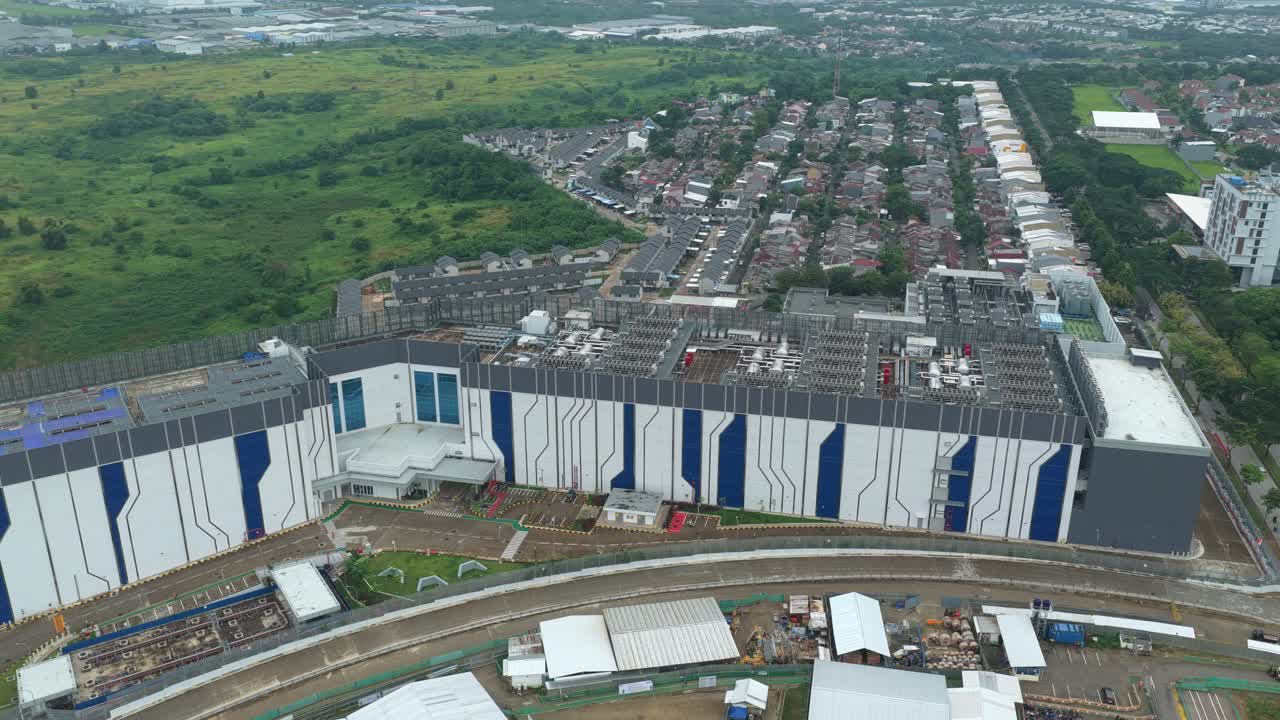 Luftfoto, der kredser om en stor, moderne datacenterbygning. Det futuristiske anlæg er placeret i udkanten af Jakarta, Indonesien