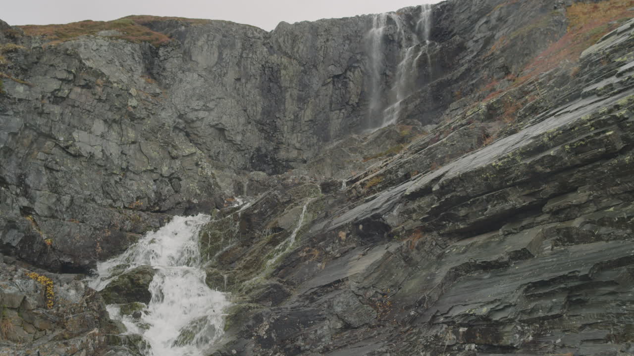 el agua fluye entre rocas en cámara lenta con cascada en el fondo