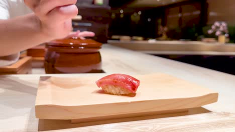 chef skillfully places sushi on wooden board