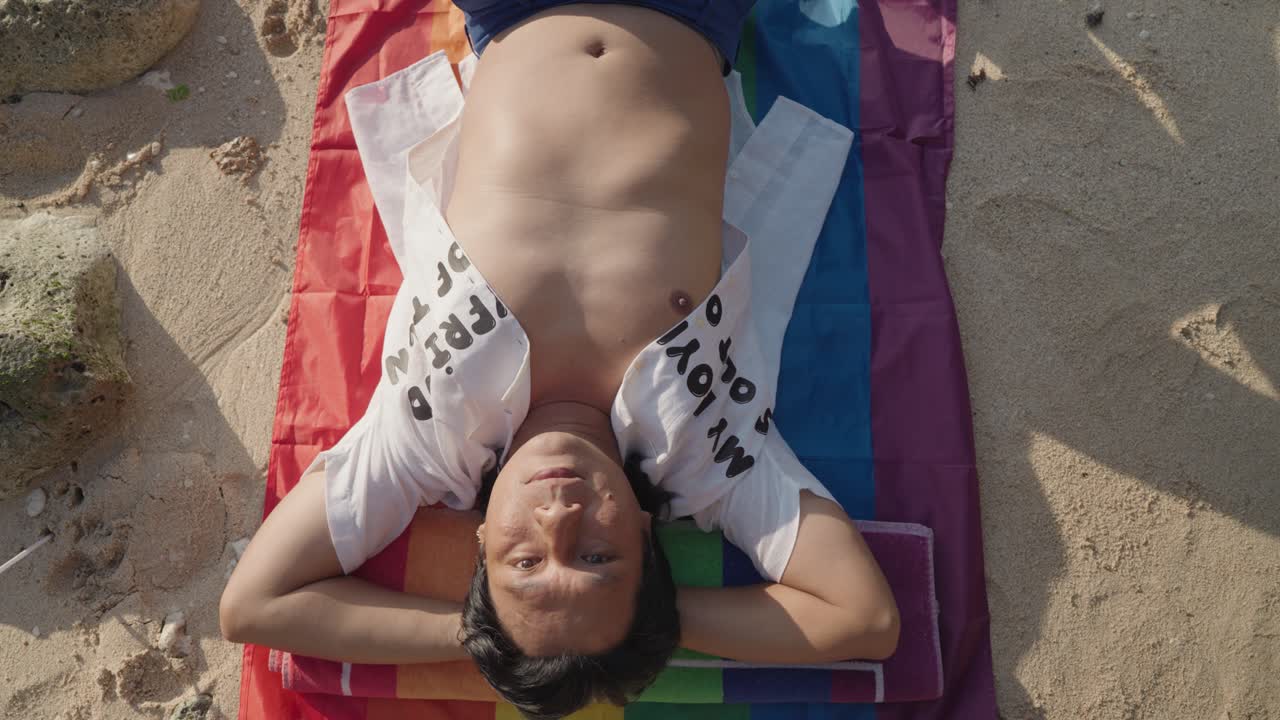 Man Relaxing on Beach with Pride Flag