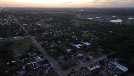High angle drone shot over American town with luxury apartment district in distance. Private lake in center of neighborhood. Sunset time in sun city, Florida. Main Street leading to town