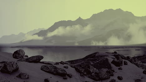 Scenic view of rocky shoreline and misty mountains at twilight