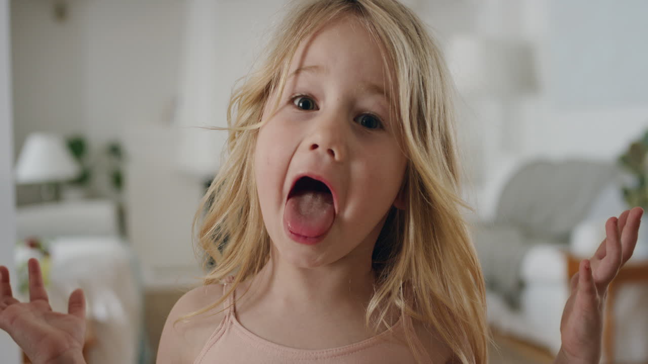 retrato de una niña divertida haciendo caras tontas mirando a la cámara un niño feliz disfrutando juguetón de la infancia divirtiéndose en casa 4k