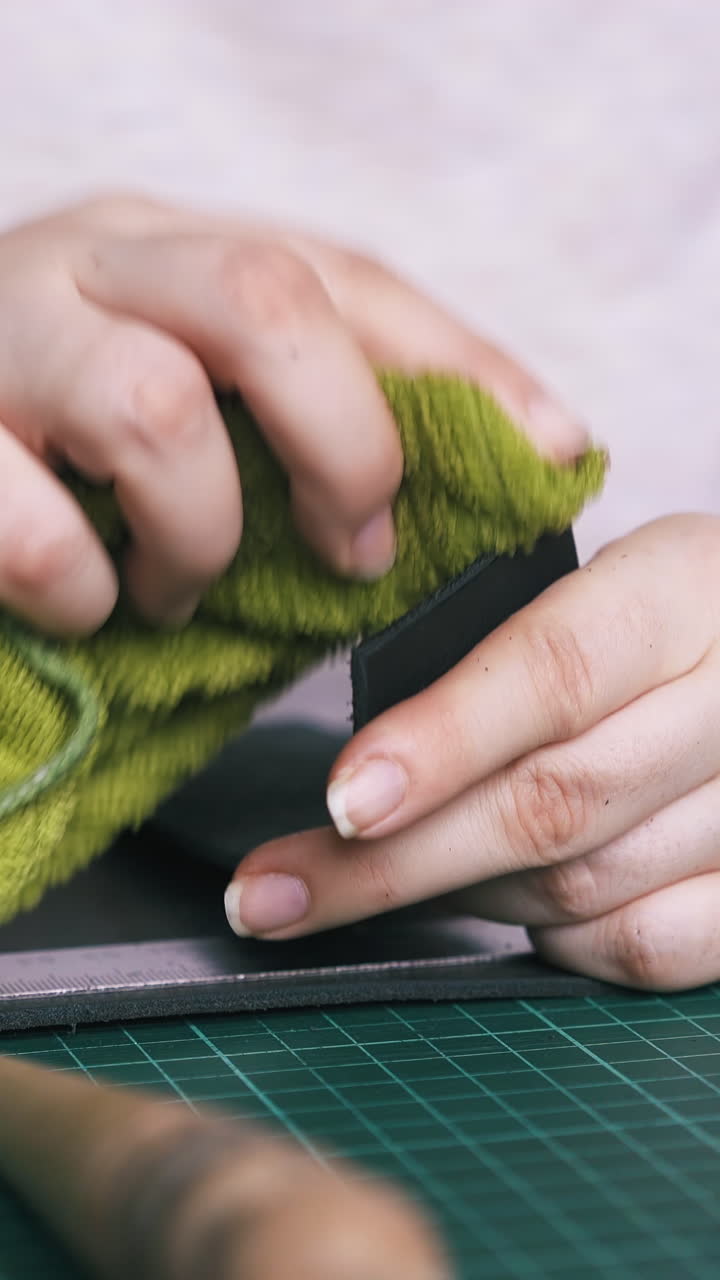 CU: Skilled woman tailor wipes leather cloth edge with wet towel and polishes with brown slicker close view