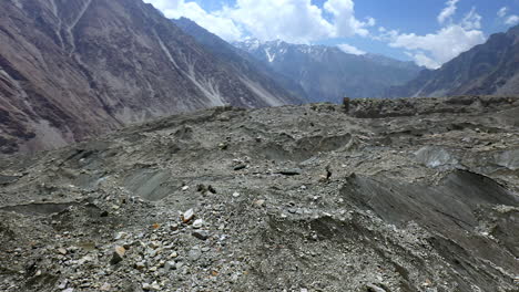 drone shot of man standing on mountain peak, passu cones pakistan, rotating aerial shot