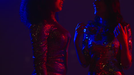 Close-Up-Of-Two-Women-In-Nightclub-Bar-Or-Disco-Dancing-Talking-And-Having-Fun-Together