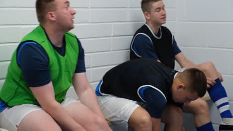 Soccer players in locker room listening to coach giving pre-game pep talk