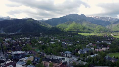 Flyover-of-Zakopane,-Poland,-a-resort-town-village-with-traditional-Goral-architecture-near-the-Polish-Tatra-mountains,-farmland,-forests,-Giewont-peak,-and-Great-Krokiew-Ski-Jump---4K-Tracking-Back