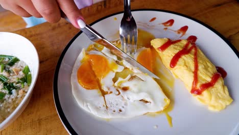 person cutting fried egg and omelette