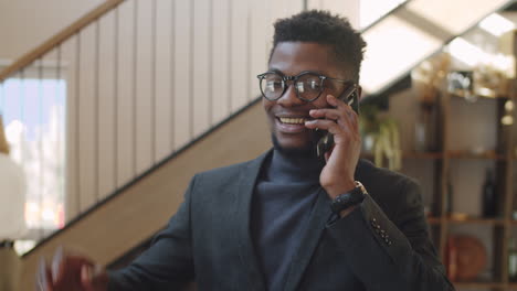 Positive-Black-Businessman-Walking-in-Office-and-Speaking-on-Phone