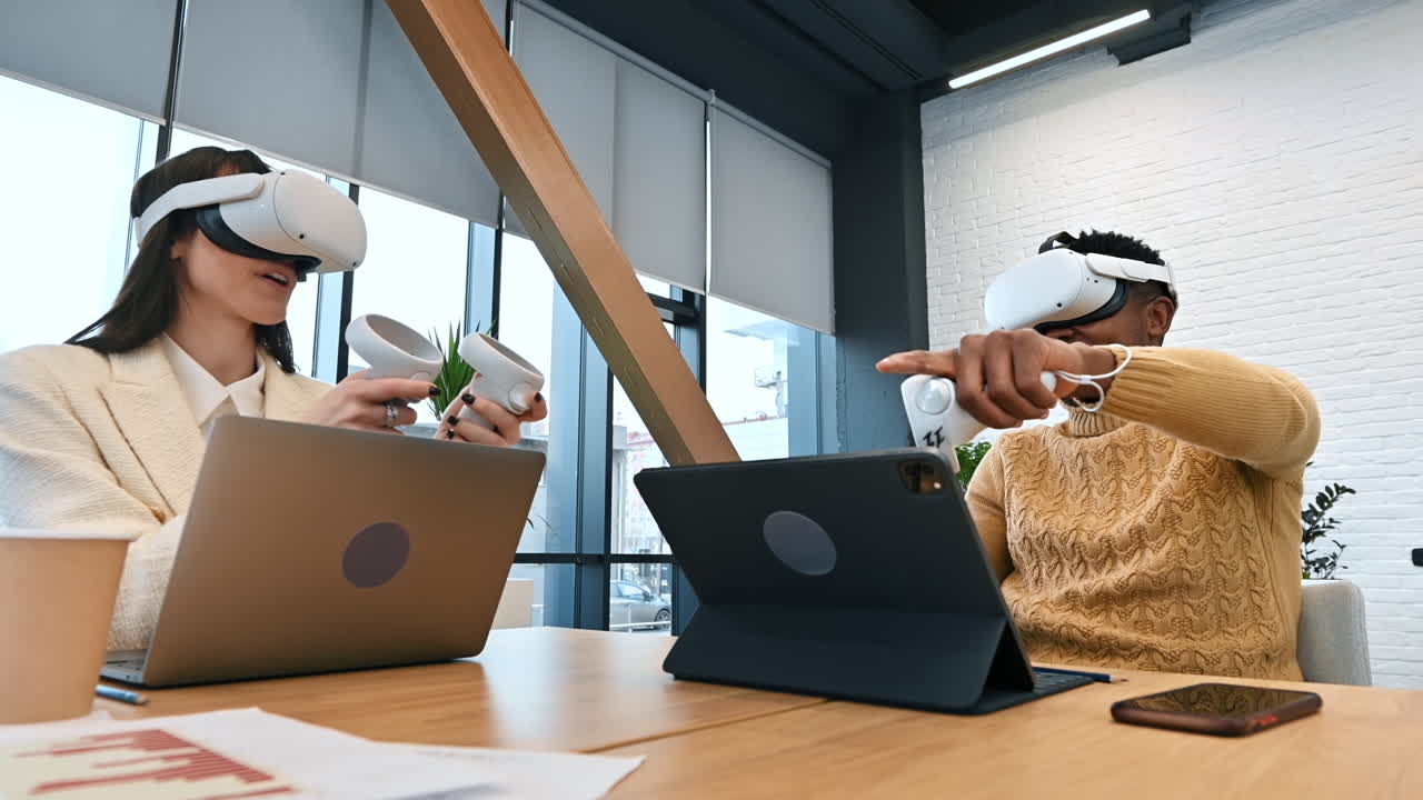 Business conference in VR in an office. A black man and caucasian woman using VR glasses and controllers, gadgets on the table. Slow motion