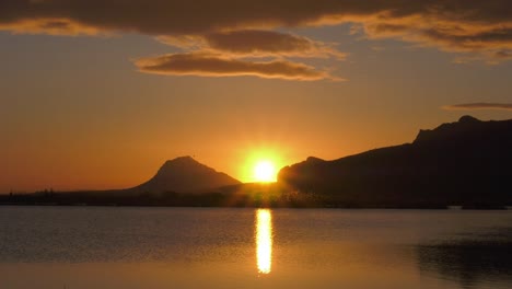 Sunrise-over-mountains-reflecting-in-calm-lake,-zoom-out