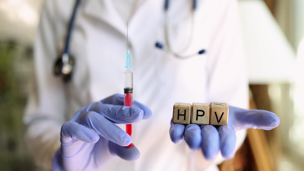 Doctor holding HPV vaccine syringe and blocks spelling HPV