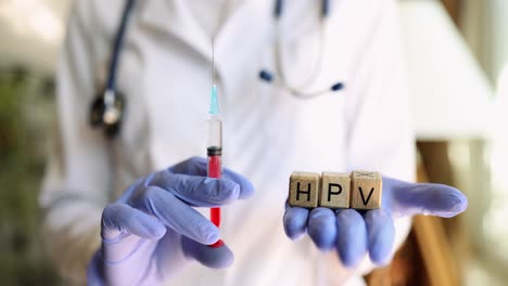 doctor holding hpv vaccine syringe and blocks spelling hpv