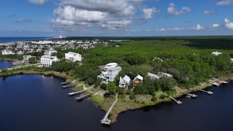 Backward orbiting aerial fly from the white houses along Camp Creek Lake near coastline, 30A, Florida, USA