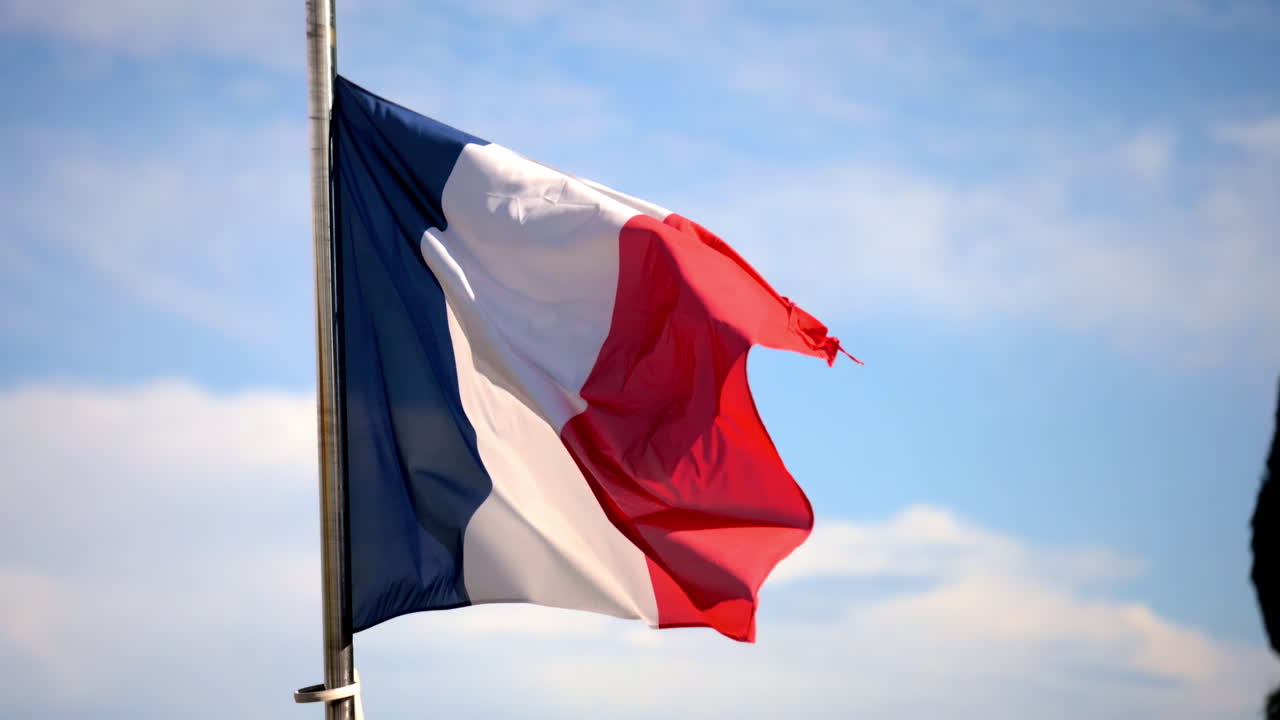 Primo piano della bandiera francese che sventola nel vento con un cielo blu sullo sfondo