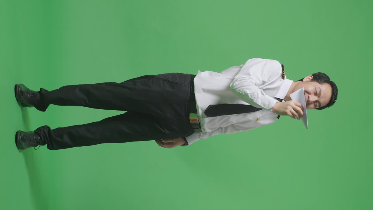 프로 유니폼을 입은 아시아 남성 조종사가 종이 비행기를 발사하고, 제트 모델을 손에 들고, 항공 아카데미 조종사, 녹색 스크린 배경 스튜디오에서 항공기 선장
