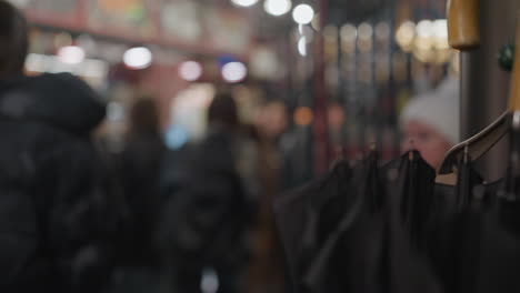 close view of black umbrellas on a rack, with people blurred in the background