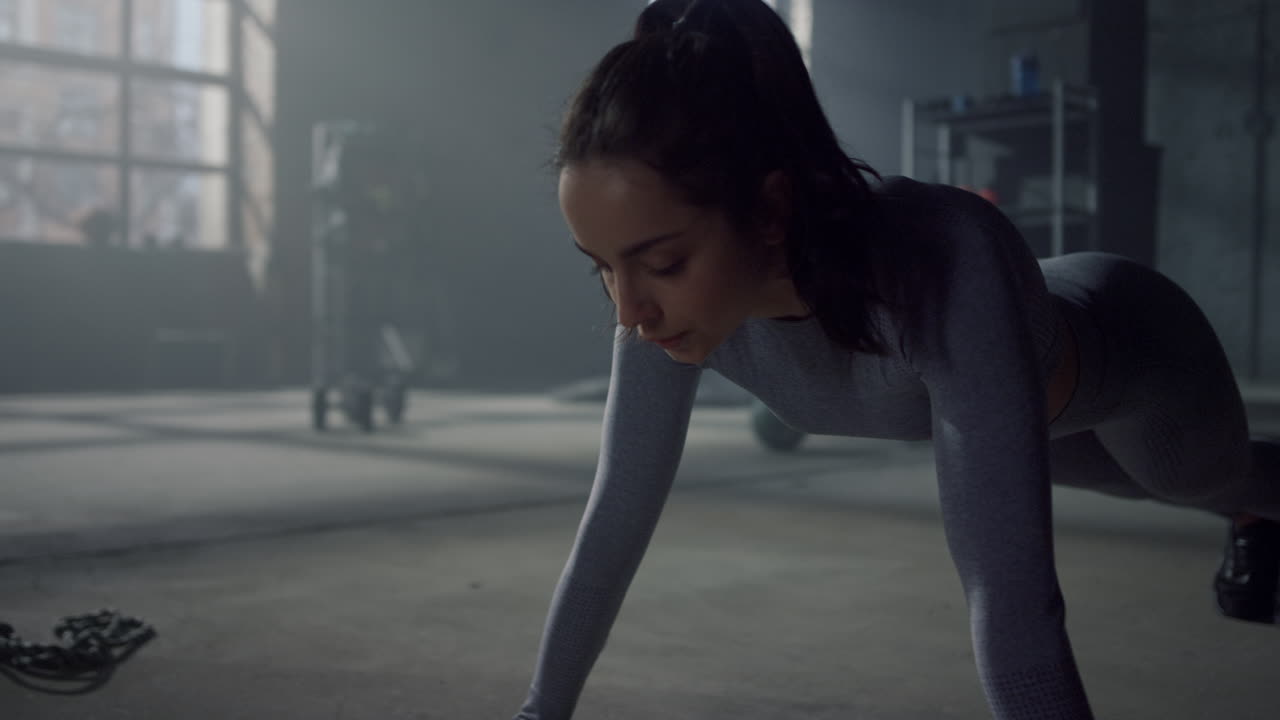 Woman doing push ups on floor in gym. Bodybuilder making fitness exercise in plank