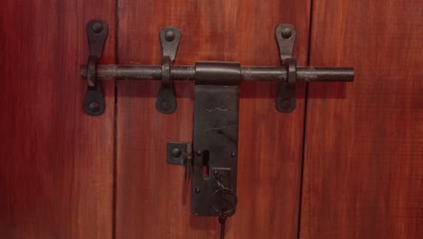 close-up of a rustic, metal latch on a wooden door with natural lighting