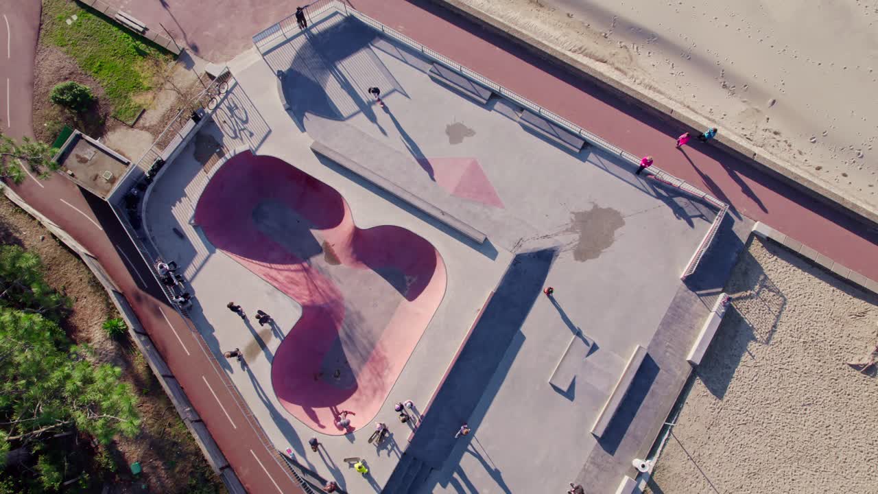 Unge mennesker nyter fritiden på en solrik dag i skateparken, luftfoto ovenfra.