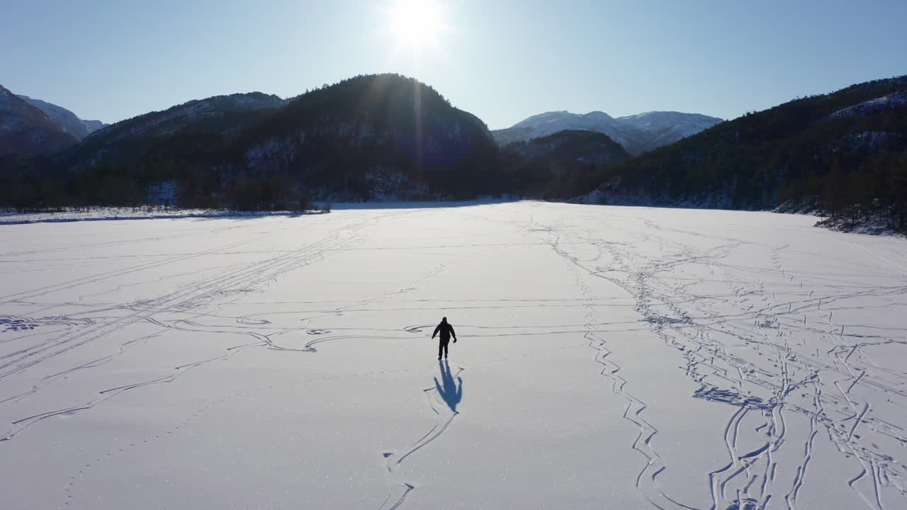 seguimiento aéreo patinador sobre hielo solo rodeado de montañas en el lago congelado - noruega