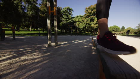 young woman wearing a face mask walks on a balance beam in a park, wide shot