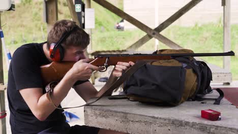 chico caucásico entrenado para disparar un rifle en un campo de tiro
