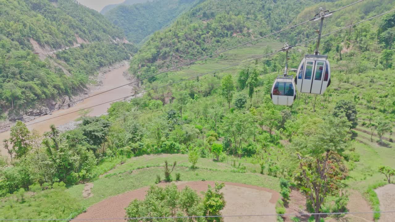 A cable car travels above a flowing river and lush green mountains, offering a stunning view of nature, elevation, and movement. Perfect for themes of travel, exploration, and scenic transportation