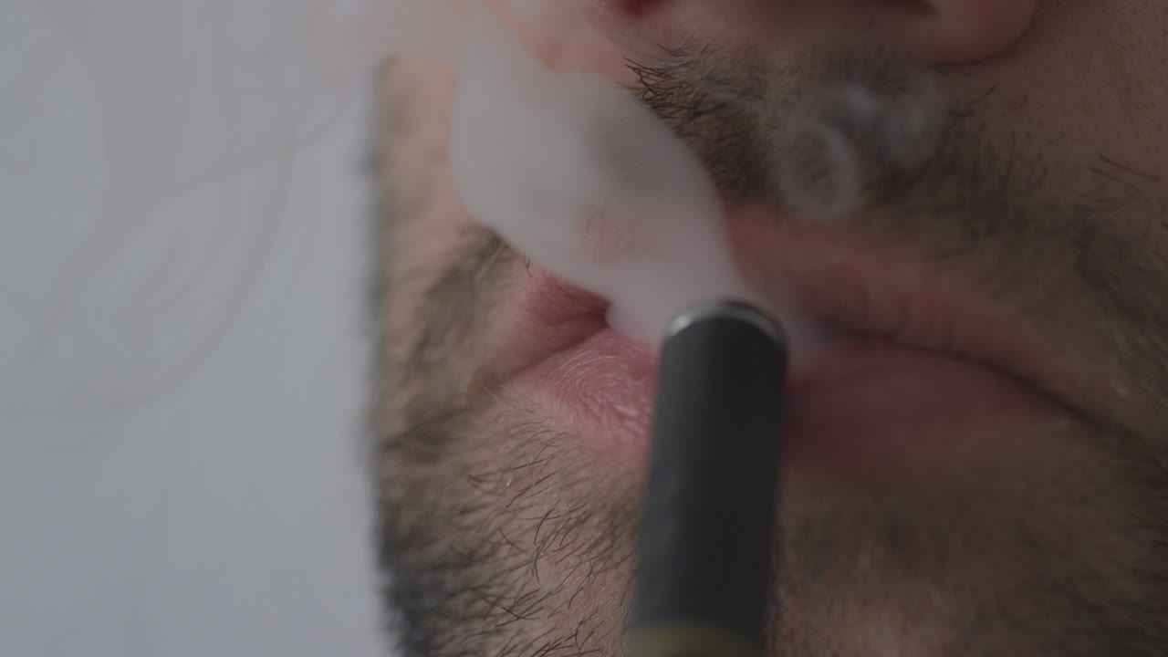 un hombre que usa una pluma de vape que inhala cannabis con nicotina o cbd con sabor