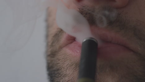 a man using a vape pen inhaling nicotine cannabis or flavoured cbd