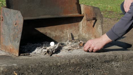 man cooking marshmallow in embers