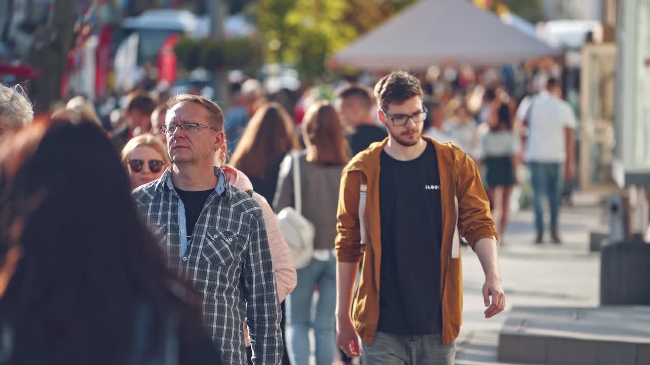 Busy city street. People walking along and back the street in warm sunny day. Crowd of people in a big city.