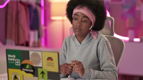 a young black woman works on her laptop at home.