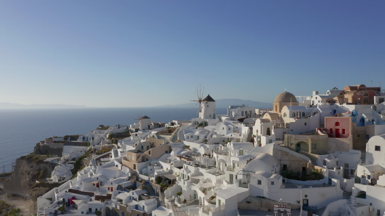 antena: tiro de drone de panorámica lenta de oia en santorini, grecia durante la hora dorada