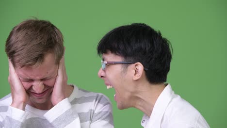 분노한 젊은 아시아 사업가들이 청년 스칸디나비아 사업가들에게 소리를 지르면서 귀를 감고 있다.