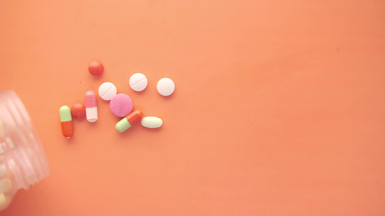 Assorted pills and capsules spilling from a bottle