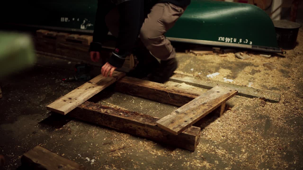 un hombre está usando un taladro para insertar clavos y asegurar la tabla de madera - tiro estático