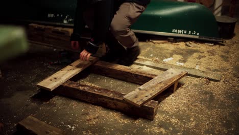 un hombre está usando un taladro para insertar clavos y asegurar la tabla de madera - tiro estático