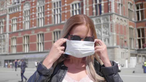 lovely dutch woman with sunglasses wears face mask in amsterdam, netherlands - close up, slow motion